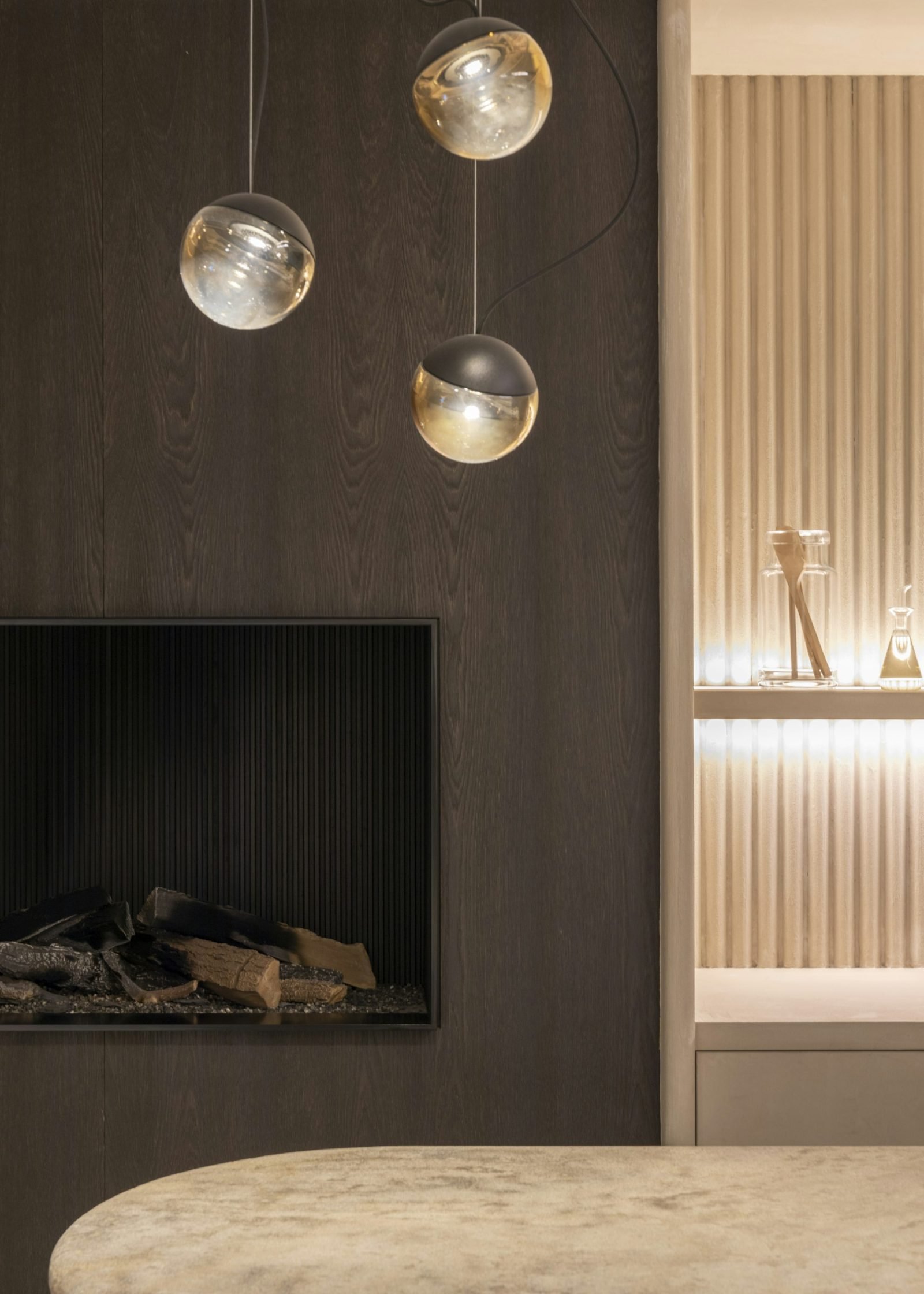 Pendant lights and a dark wood wall with fireplace